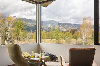 Cozy seating area in Wilderness Meadow with a view of mountains and autumn foliage through large windows.