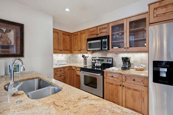 The kitchen in Woodrun Place 04 features stainless steel appliances and ample counter space, including a double sink and a granite countertop.
