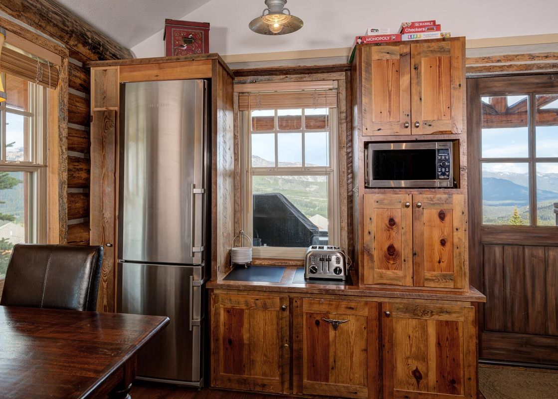 The kitchen at Moonlight Basin 9 Cabin Hollow features stainless steel appliances and rustic wood cabinetry.