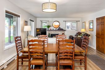 A spacious dining and living area in the All Seasons 2 Bedroom Platinum Unit A1B features a large wooden dining table with chairs, an inviting living room with comfortable seating, and a fireplace.