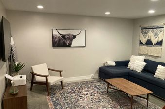 A cozy living room in the Mountain Modern Duplex with a large blue sectional sofa, a coffee table, and a unique wall tapestry.