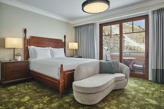 A luxurious bedroom within the Montage Alpine Residential Suite features a wooden four-poster bed with white linens, two bedside tables with lamps, a modern chaise lounge, and a large glass door leading to a balcony with mountain views.