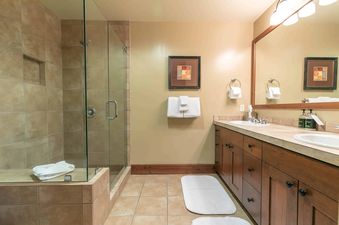 A modern bathroom with a walk-in shower, double vanity, and white towels.
