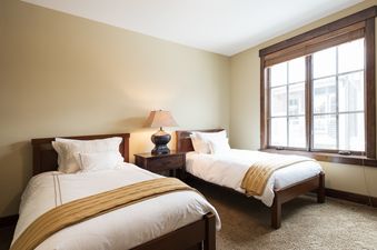 The two twin beds in Silver Star 404 are neatly made with white bedding and mustard yellow throws, separated by a nightstand with a lamp.