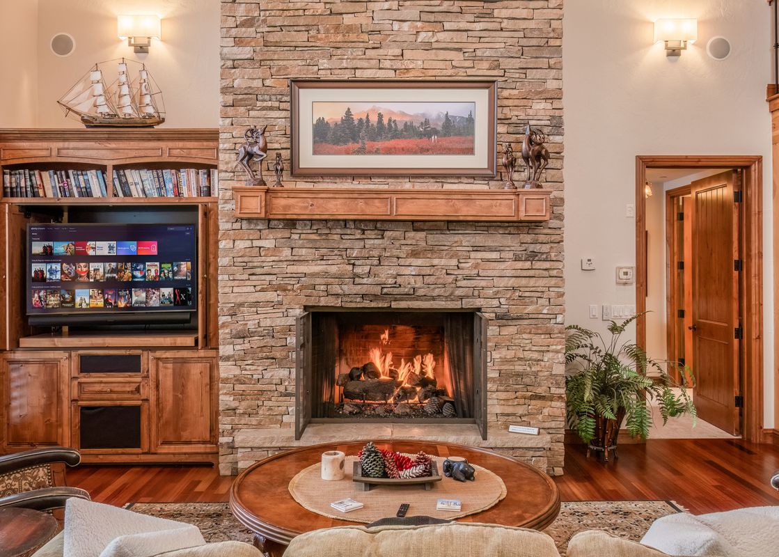 A living room with a stone fireplace, two leather chairs, and a wooden coffee table.