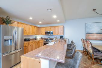 A kitchen with stainless steel appliances, wooden cabinets, and a granite countertop