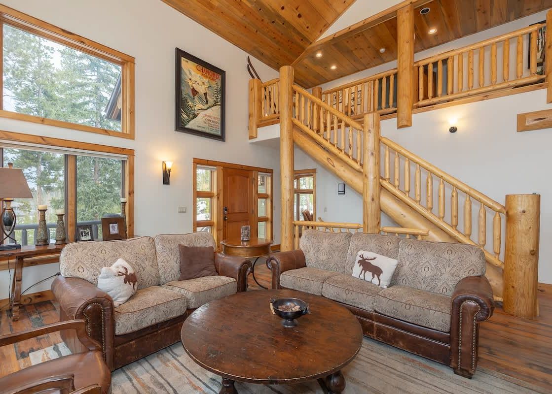 The Mountain Majesty Winter Park features a cozy living area with comfortable sofas and a rustic wooden coffee table, perfect for relaxation after a day of skiing.