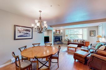 Open-plan dining and living area in Meadows Sheffield 3, featuring a round wooden table, leather seating, and a corner fireplace.