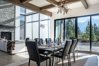 A modern dining room with a large window overlooking a mountain view.