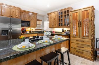The kitchen at Bear Hollow 5428 features wood cabinetry, black granite countertops, and stainless steel appliances.