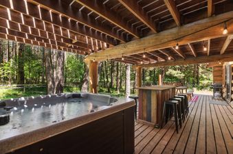 The covered outdoor hot tub and bar area at Apres Chalet, perfect for relaxation and entertaining amidst a serene forest backdrop.