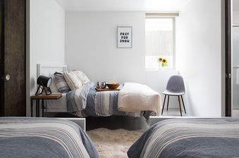 Bright guest bedroom at Taminah Retreat with striped bedding, a shaggy rug, and a "PRAY FOR SNOW" sign.