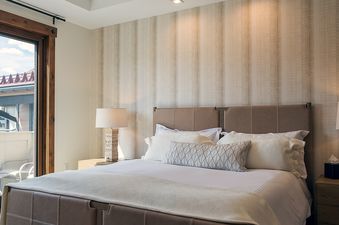A modern and elegant bedroom in Emerald Mountain One Steamboat Place 702 with a king bed, bedside lamps, and access to a balcony.