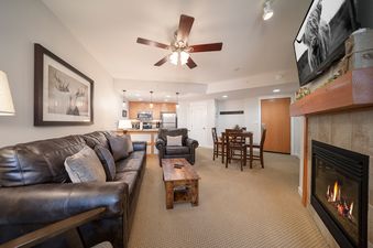 The living area of Fraser Crossing 3509, featuring comfortable seating, a dining area, and a kitchen.