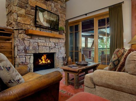 Cozy living room with a stone fireplace, television, and plush seating in Crystal Springs 403.