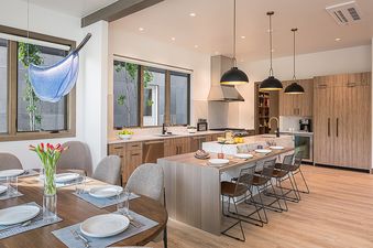 A modern kitchen and dining area in Riverlight Lodge, featuring a large island with bar seating, a dining table, and natural wood finishes.