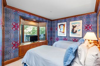 The bedroom in Plaza Lodge 3 Bedroom Gold Unit 2 features two beds, an elegant red and blue patterned wallpaper, and a bay window.