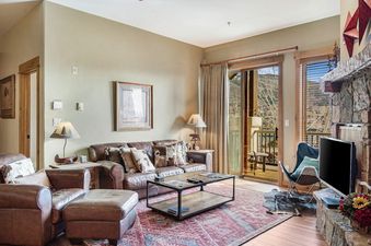 Cozy living room at EagleRidge Lodge 306 with leather seating and a stone fireplace.