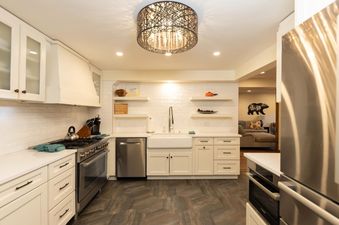 A modern kitchen with white cabinets, stainless steel appliances, and a unique wire chandelier.