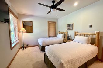 A cozy bedroom at Rendezvous A 6 with two twin beds featuring rustic log headboards and crisp white linens.