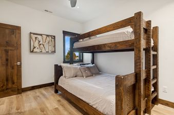 A cozy bunk room at Columbia Crest 301 features a sturdy wooden bunk bed with patterned bedding, a window with an outdoor view, and light wood floors.
