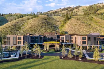 An aerial view of The Sylvan Lodge Four Bedroom Junior Penthouse, nestled against green, tree-covered mountains under a bright sky.