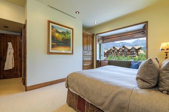 The bedroom at Peaks Penthouse 702 boasts a large window with stunning mountain views and a cozy bed, creating a serene and luxurious retreat.