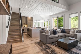An inviting open-concept living space with a large L-shaped sofa, a modern coffee table, and an adjacent kitchen island.