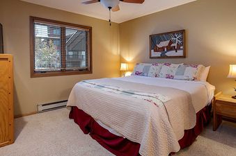 A cozy bedroom at Ranch at Steamboat RA606 with a comfortable bed, warm lighting, and a view of the outdoors.