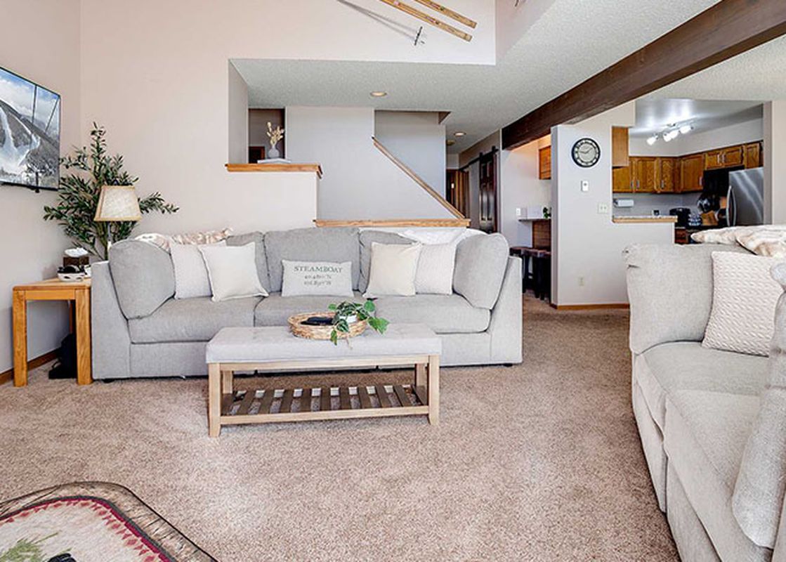 An aerial view of the open concept living area at Ranch at Steamboat RA216, featuring a gray sectional, wooden coffee table, and a view into the kitchen.