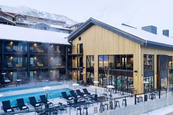 An elevated winter view of the heated outdoor pool and modern lodge at Gravity Haus JH Premium Loft Suite.