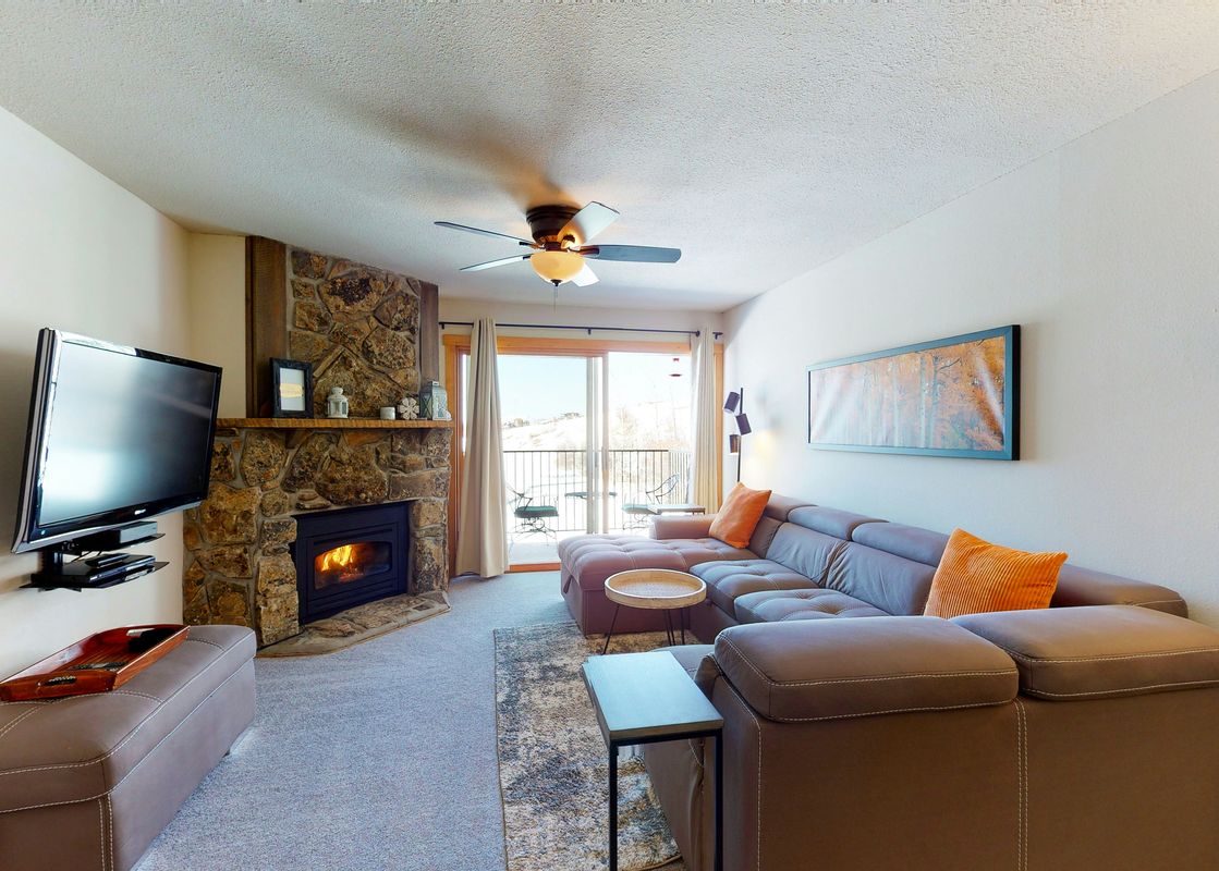 Living room with a fireplace, a couch, a TV and a view of the mountains from a window