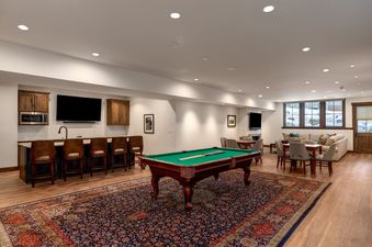 Spacious games room with a pool table, bar counter with seating, and a cozy lounge area at The Bear and Moose Lodge.