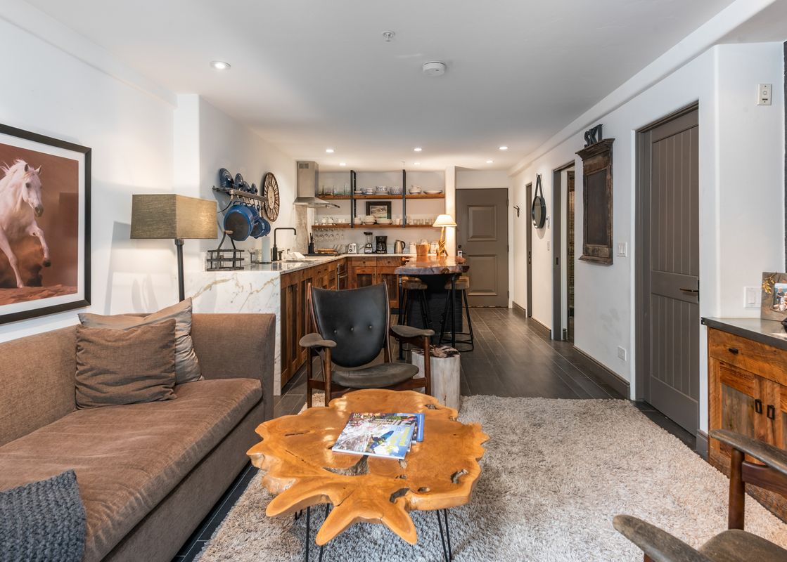 The open-concept living area of Bridge Street Lodge 2 Bedroom Diamond Unit 306, featuring a comfortable sofa, a unique wood coffee table, and a well-appointed kitchen.