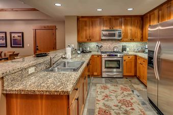 A modern kitchen with stainless steel appliances, wooden cabinets, and granite countertops.