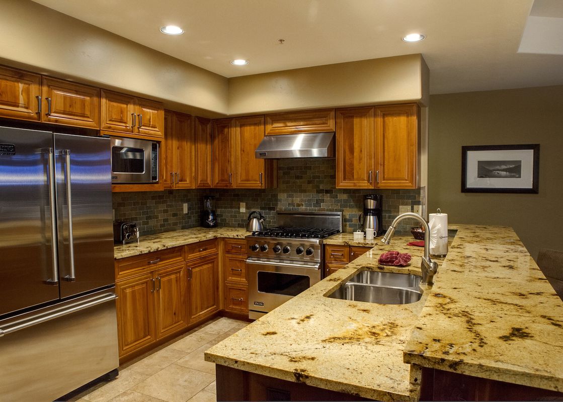 The kitchen at Crystal Peak 3 Bedroom features rich wood cabinetry, stainless steel appliances, and granite countertops.
