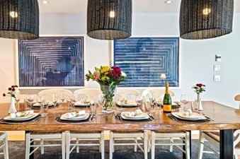 A formal dining area at St Moritz Townhomes with a large wooden table, elegant place settings, fresh flowers, and modern pendant lights.