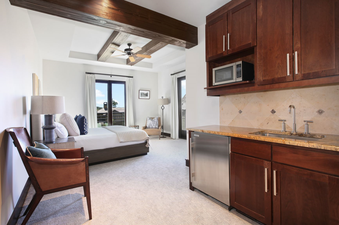 A cozy, well-appointed kitchenette features stainless steel appliances and a granite countertop. The space is open to the bedroom and features a view of the surrounding mountain scenery.