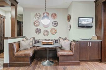A cozy dining nook in Flagstaff 204 with brown leather bench seating, a round table with a game box, and decorative woven plates on the wall, lit by a modern pendant light.