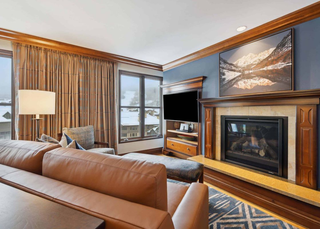 The living area at Park Hyatt 4051 features a comfortable brown leather sofa, a grand fireplace, and a large flat-screen TV.