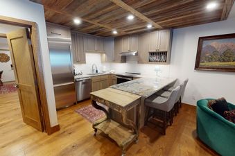 The kitchen in Manor Vail 148A features stainless steel appliances, granite countertops, and a breakfast bar.