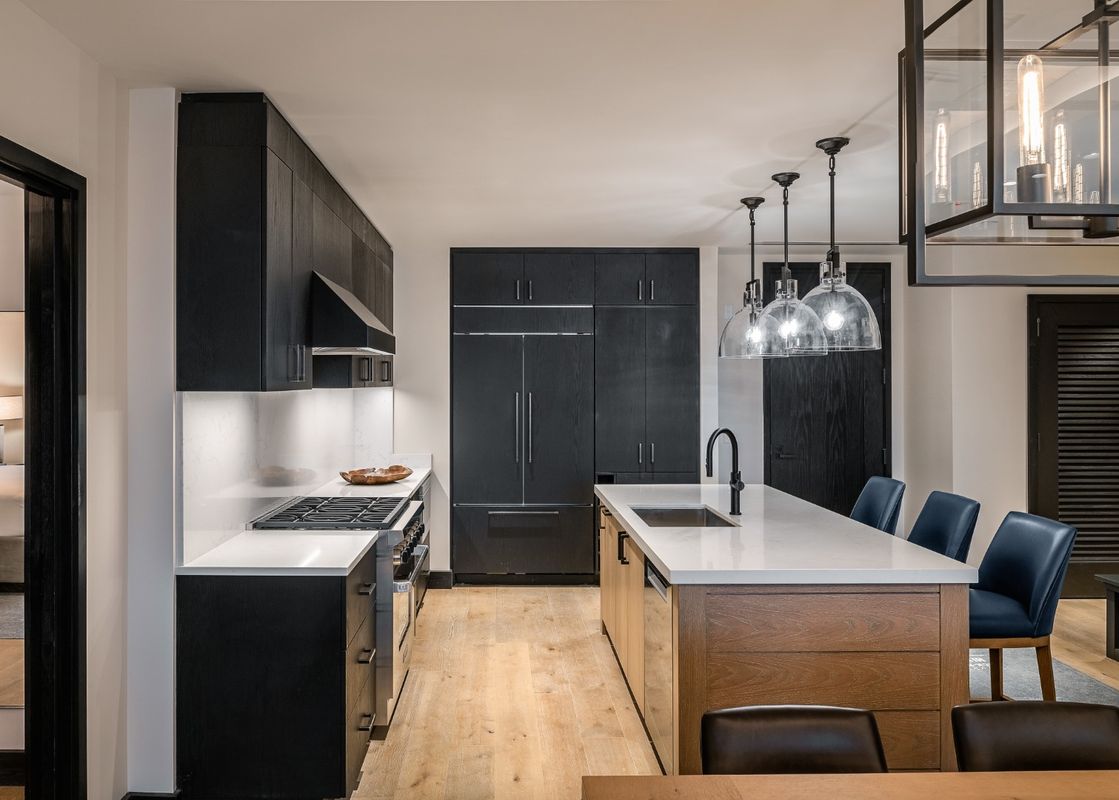 A modern kitchen with black cabinets, stainless steel appliances, and a large island with seating.