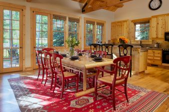 Dining table with red chairs and adjoining kitchen inside Granite Ridge Homestead 3072.