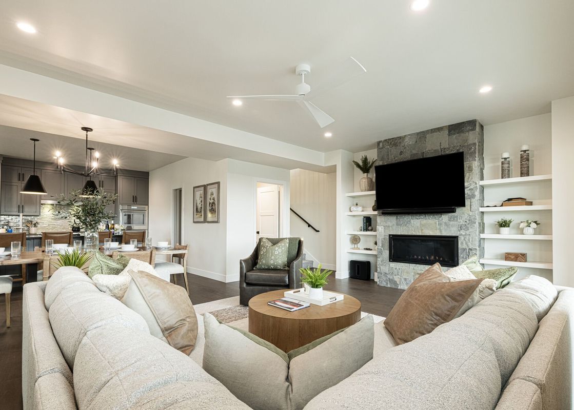The living area of Deer Valley Daystar 1793 features a comfortable U-shaped sofa, a round coffee table, and an armchair, with a stone fireplace and television on the right.