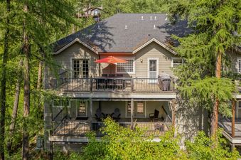 The Bitterroot Escape is a two-story house with multiple balconies nestled among tall green trees.
