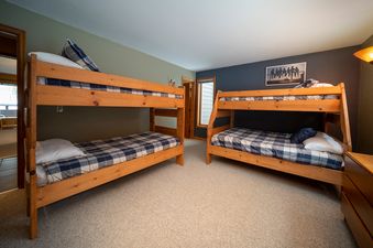 A cozy bedroom with two wooden bunk beds, featuring blue and white plaid bedding, provides comfortable sleeping arrangements in Iron Horse J1309.