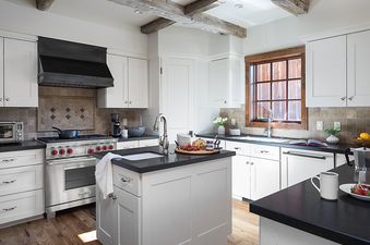 The spacious kitchen at Shooting Star Cabin 11 boasts white cabinetry, state-of-the-art appliances, and a central island, creating an inviting space for culinary endeavors.