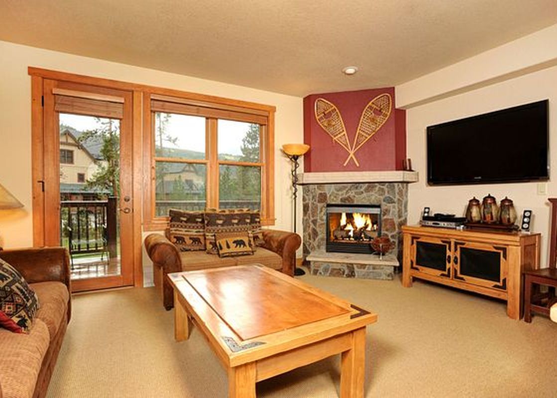 A cozy living room at Redhawk Townhome 3 Bedroom with a stone fireplace, comfortable sofas, and a coffee table, offering a warm and inviting atmosphere.
