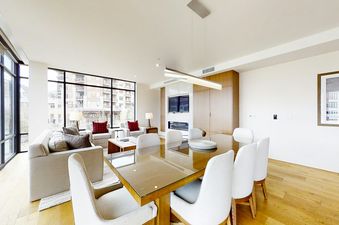 The dining room in The Lift 402 features a large glass table with six white chairs and a view of the surrounding city.