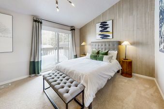 Wildflower Unit 8 bedroom has a comfortable bed with green pillows and a large window with a view of the snowy forest outside.